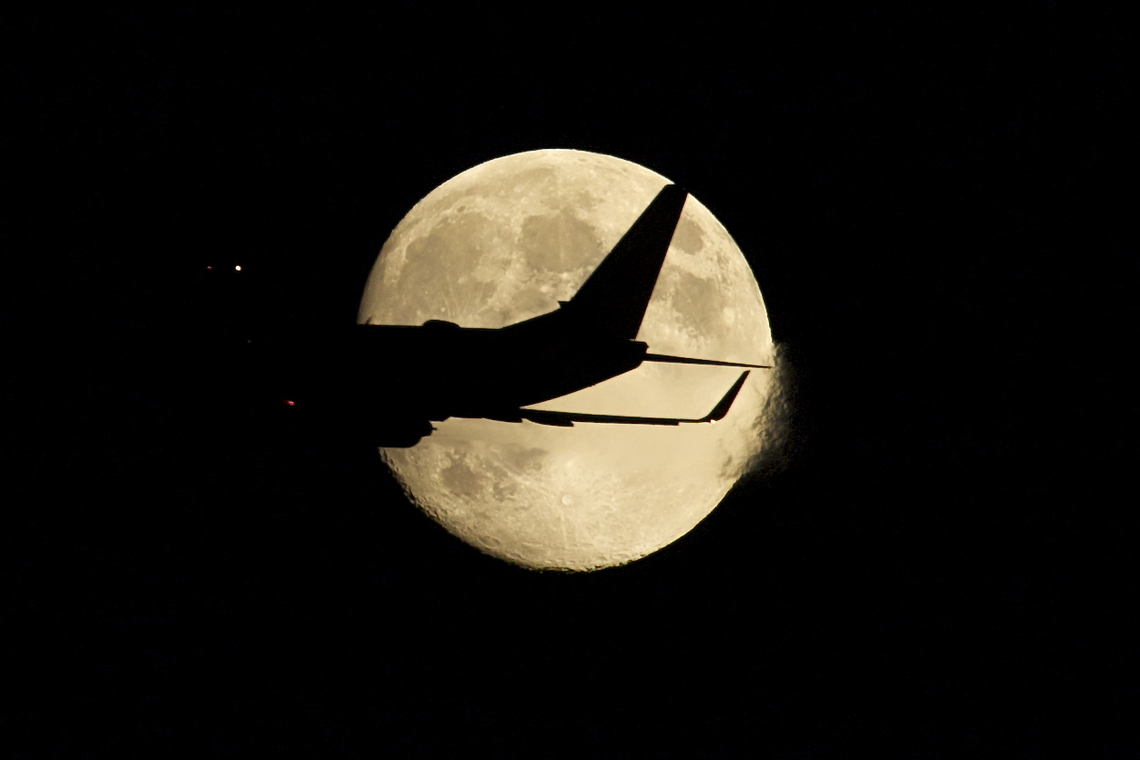 An airplane crosses the Moon as it departs Boston for another journey.(by Tamas Kolos-Lakatos)